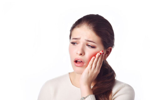 a woman holding her jaw in teeth pain