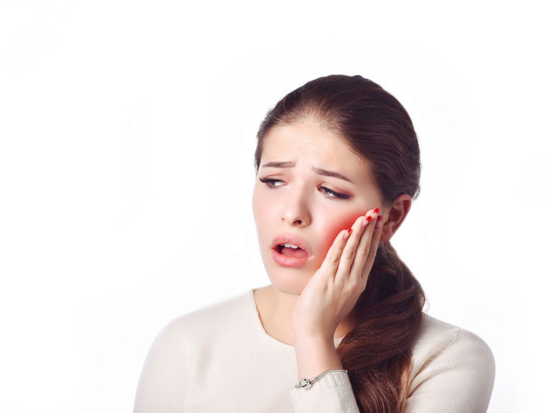 a woman holding her jaw in teeth pain